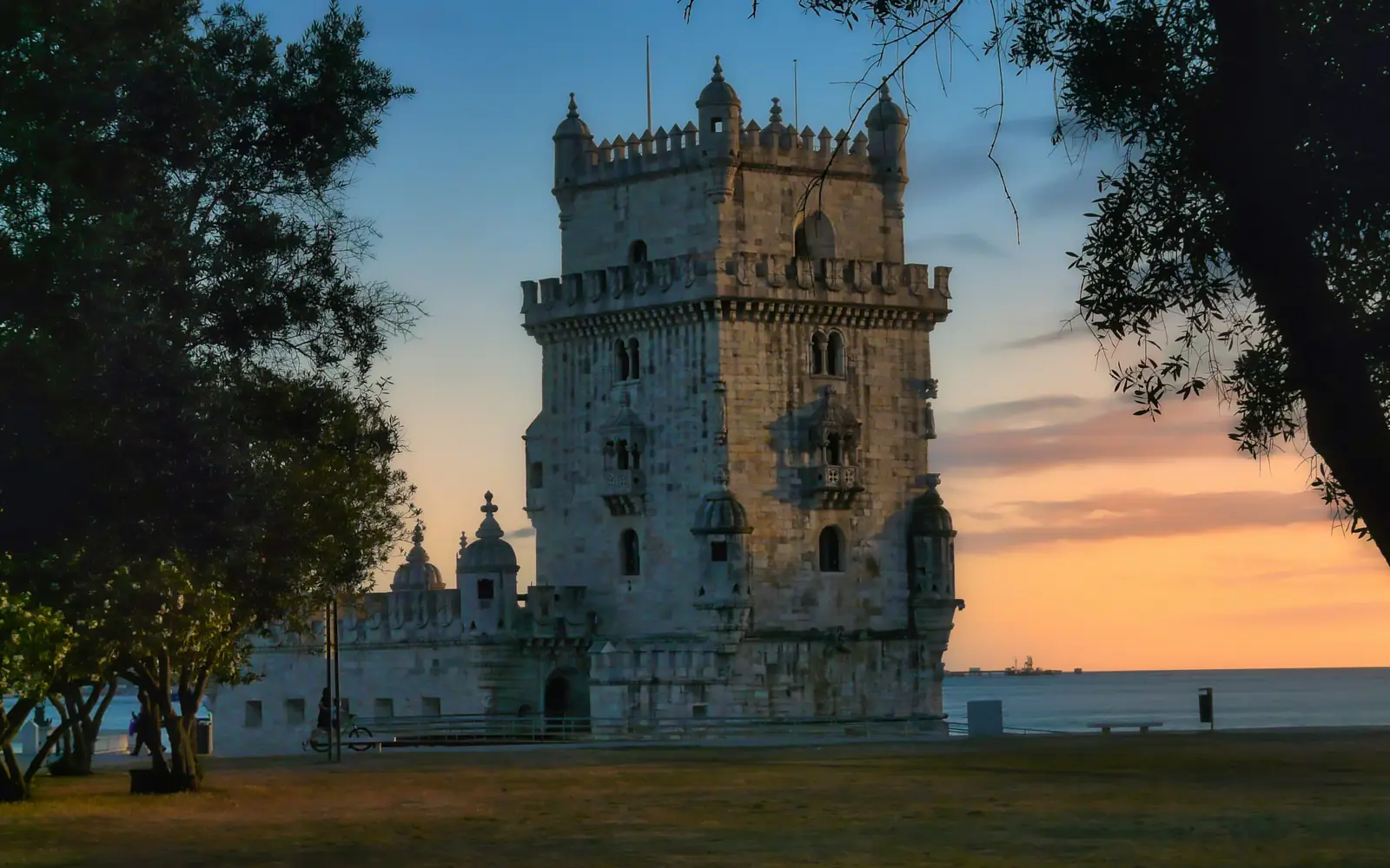 Belém Tower standing in the Tagus at sunset, its Manueline turrets lit from the west